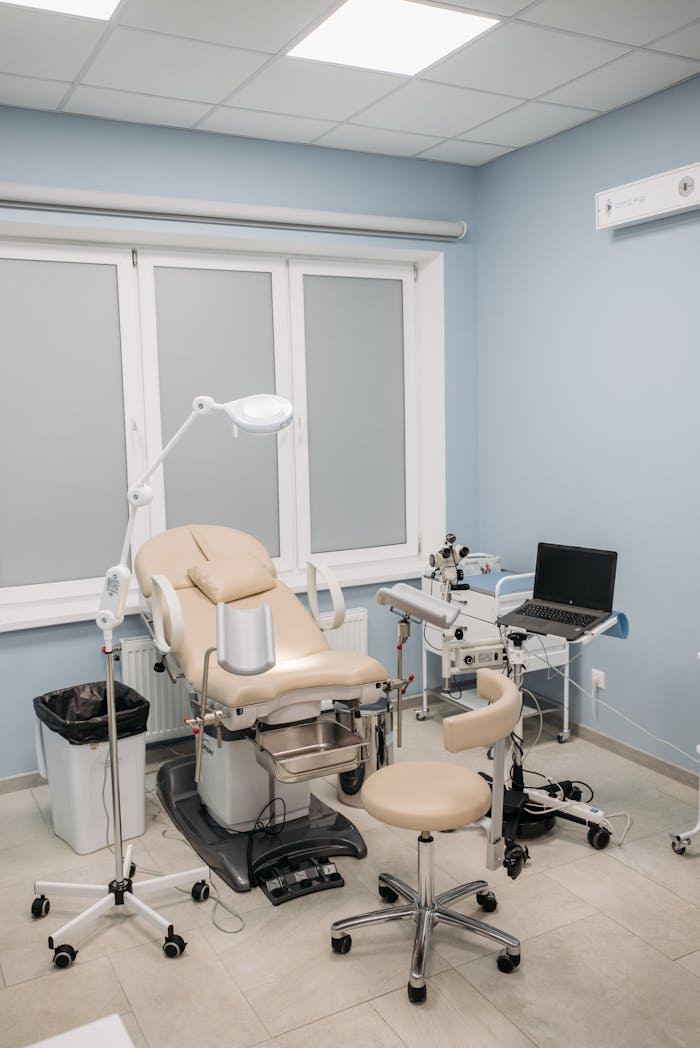 services-04 A clean and modern medical clinic examination room with equipment and chairs.