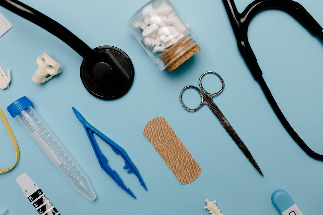 Flat lay of assorted medical tools and equipment on a blue surface.